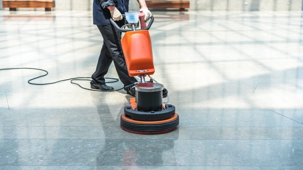 Technician polishing a stone lobby floor during commercial office cleaning in Maple Ridge