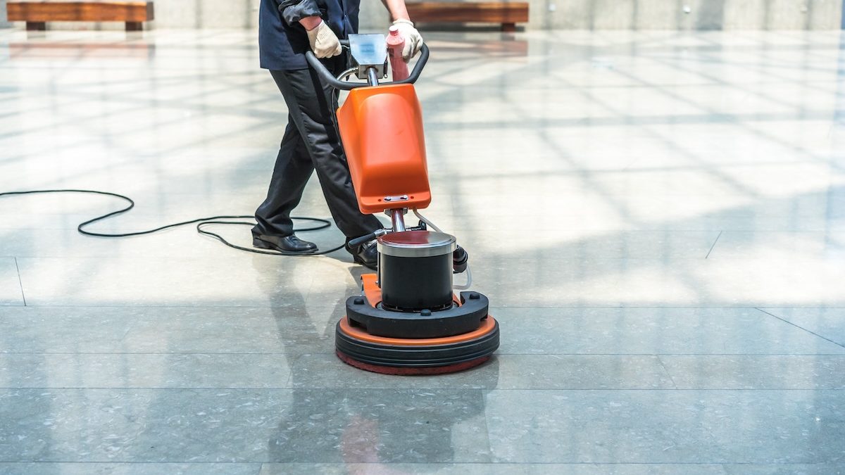 Cleaner operating a floor scrubbing machine during a commercial office cleaning job in Coquitlam